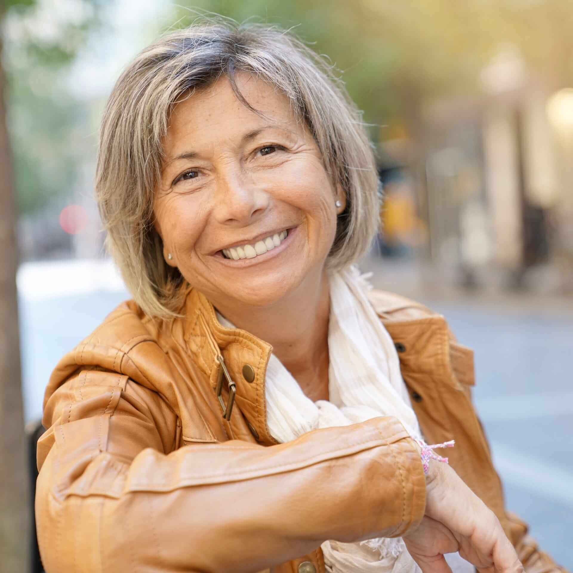 Smiling older woman sitting outside on a bench