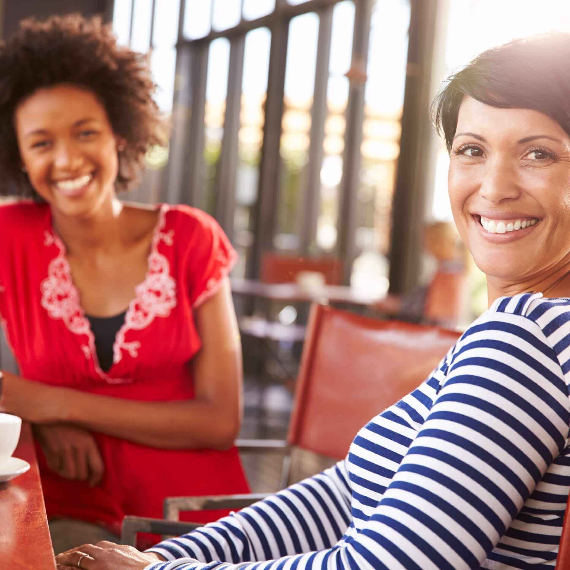 Two smiling women having coffee at a coffeehouse